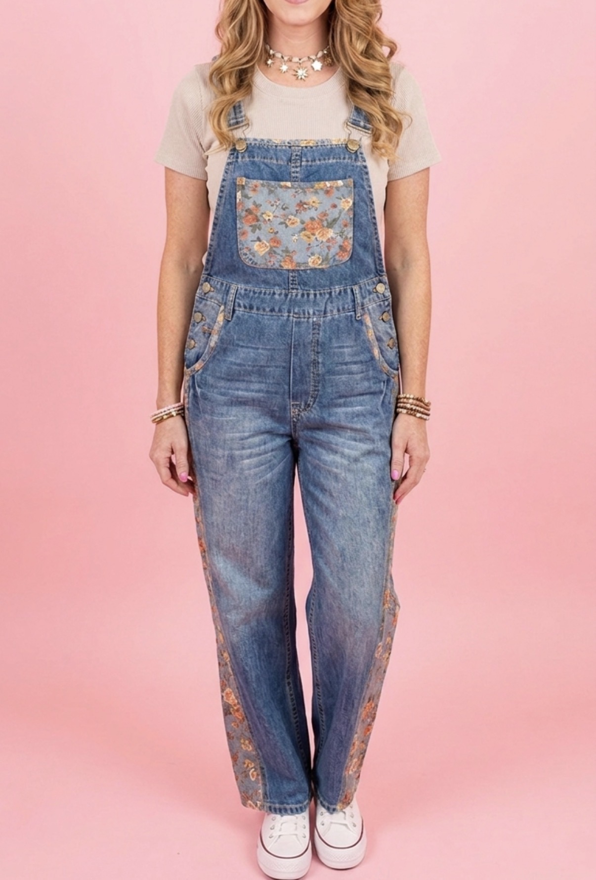 Denim overalls with floral panel detailing on a pink backdrop